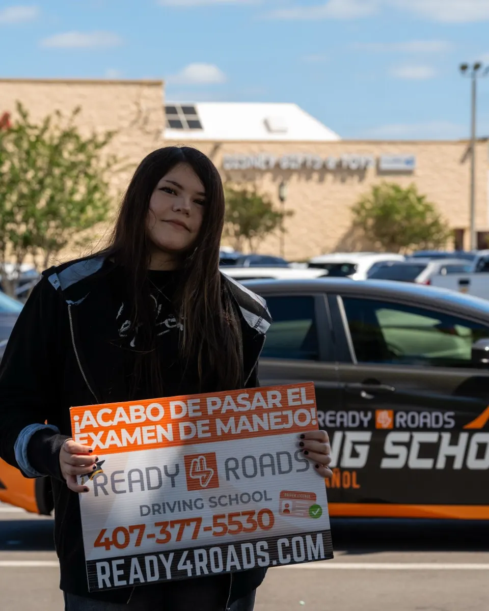 Preparación para el examen DMV en Kissimmee, FL · estudiante de Ready 4 Roads con el cartel “¡Acabo de pasar el examen de manejo!”