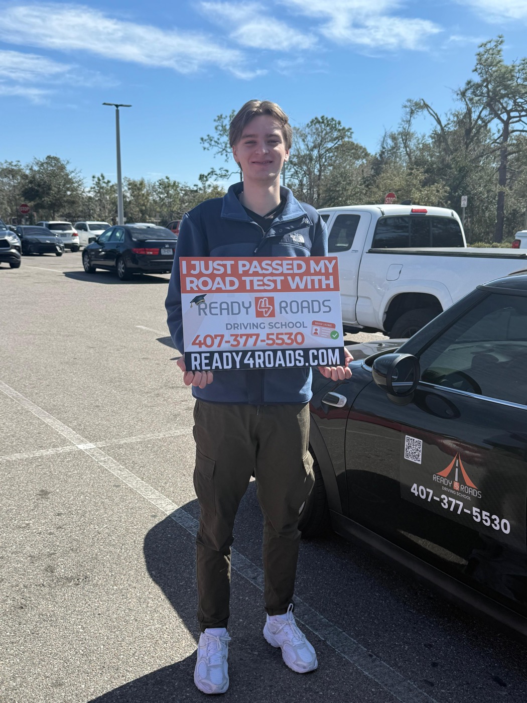 Ready 4 Roads driving school student in Kissimmee, FL holding "I just passed my road test" sign after first-try DMV pass